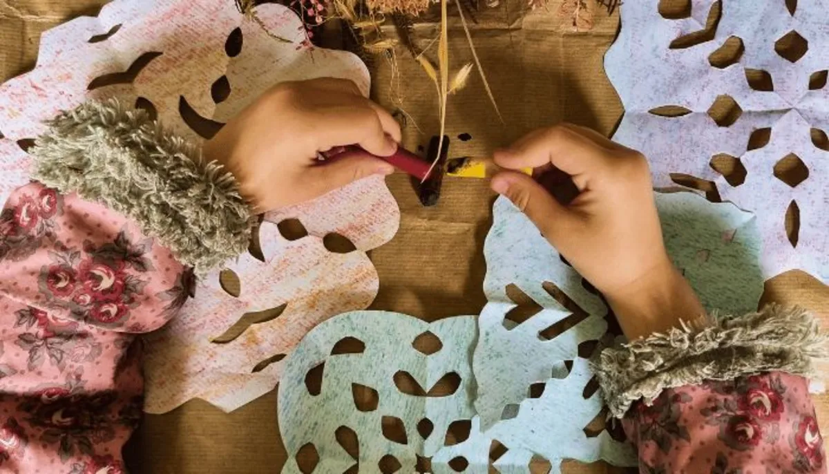 Mãos de criança criando artesanato com papel