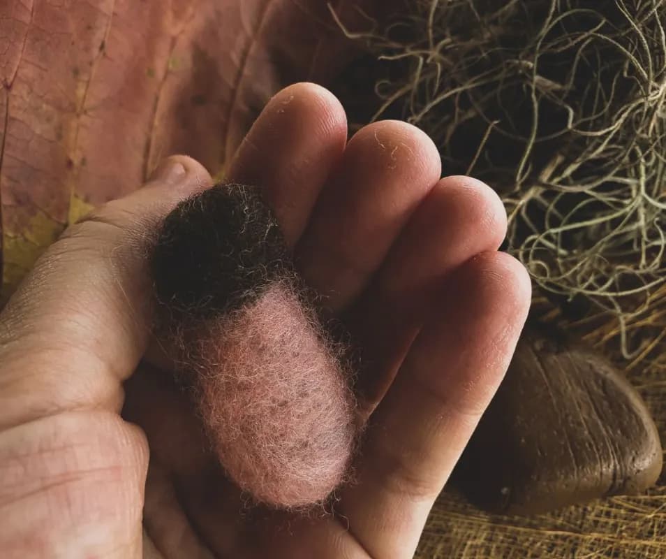 Mão segurando lã feltrada artesanal