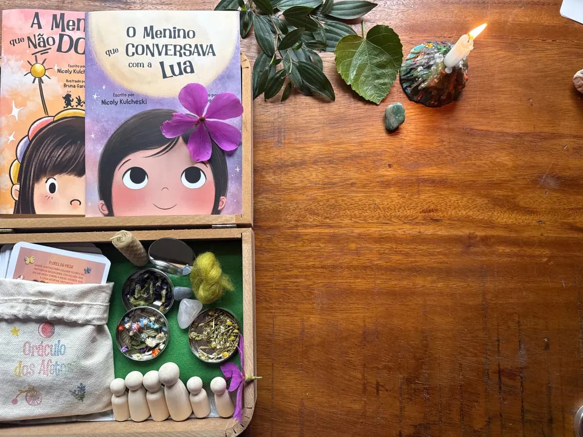 Os dois livros, a maleta Pequena Terra aberta e o saquinho do Oráculo dos Afetos juntos na mesa, à luz de uma vela