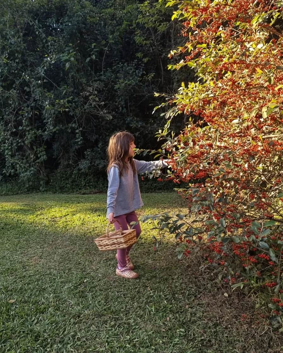 Menina com uma cestinha coletando folhas no jardim